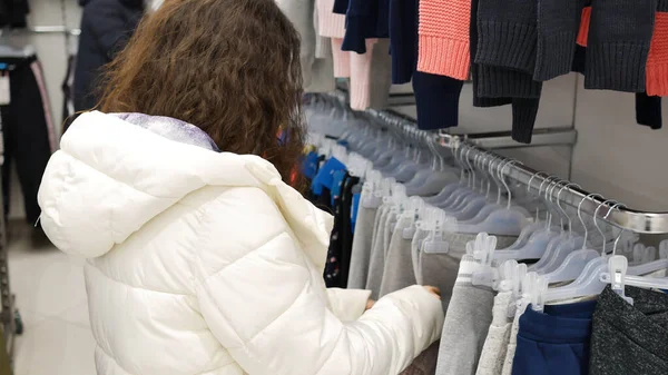 Young Woman White Jacket Chooses Clothes Shop — Stok fotoğraf