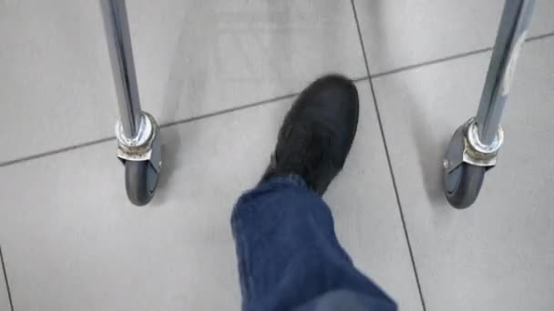 ショッピングカートで歩く男性の足のクローズアップ。スーパーで買い物した後に駐車車に購入を運ぶ男のバイヤー — ストック動画
