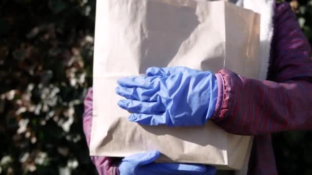 Кур'єр, чоловік-доставка в захисну маску і медичні рукавички доставляє їжу. Служба доставки в умовах карантину, епідемії хвороб, пандемії коронавірусу. Залишайтеся вдома — стокове відео