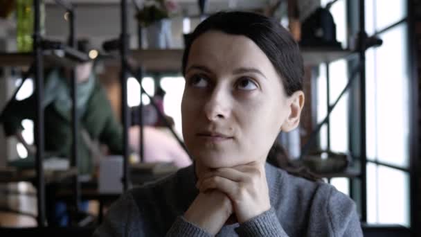 Mujer atractiva joven esperando comida en un café y mirando en dirección a la televisión — Vídeos de Stock