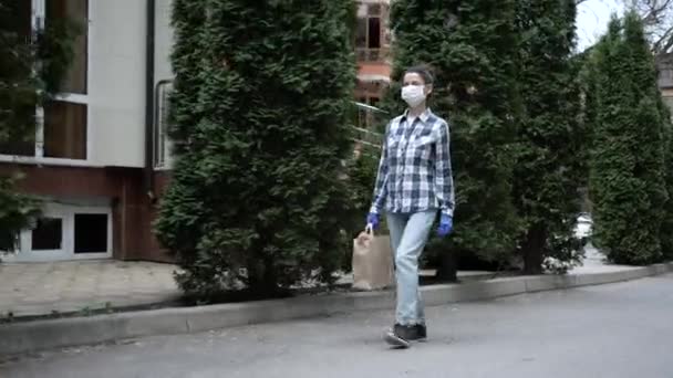 Koerier, bezorger met beschermend masker en medische handschoenen levert afhaalvoedsel. Bezorgingsdienst onder quarantaine, ziekte-uitbraak, coronavirus covid-19 pandemie. Blijf thuis. — Stockvideo