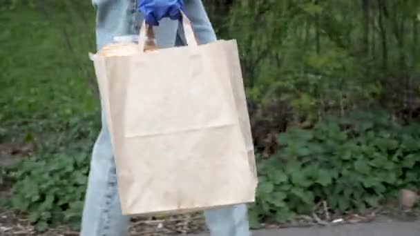 Νεαρή γυναίκα σε γάντια χωρίς επαφή λατέξ παραδίδει πακέτο με προϊόντα, αγαθά στον πελάτη κατά τη διάρκεια της περιόδου καραντίνας. τρόφιμα — Αρχείο Βίντεο