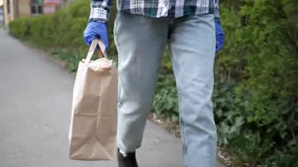 Entrega de alimentos jovem mulher em máscara protetora e luvas carrega saco com produtos da loja. pandemia — Vídeo de Stock