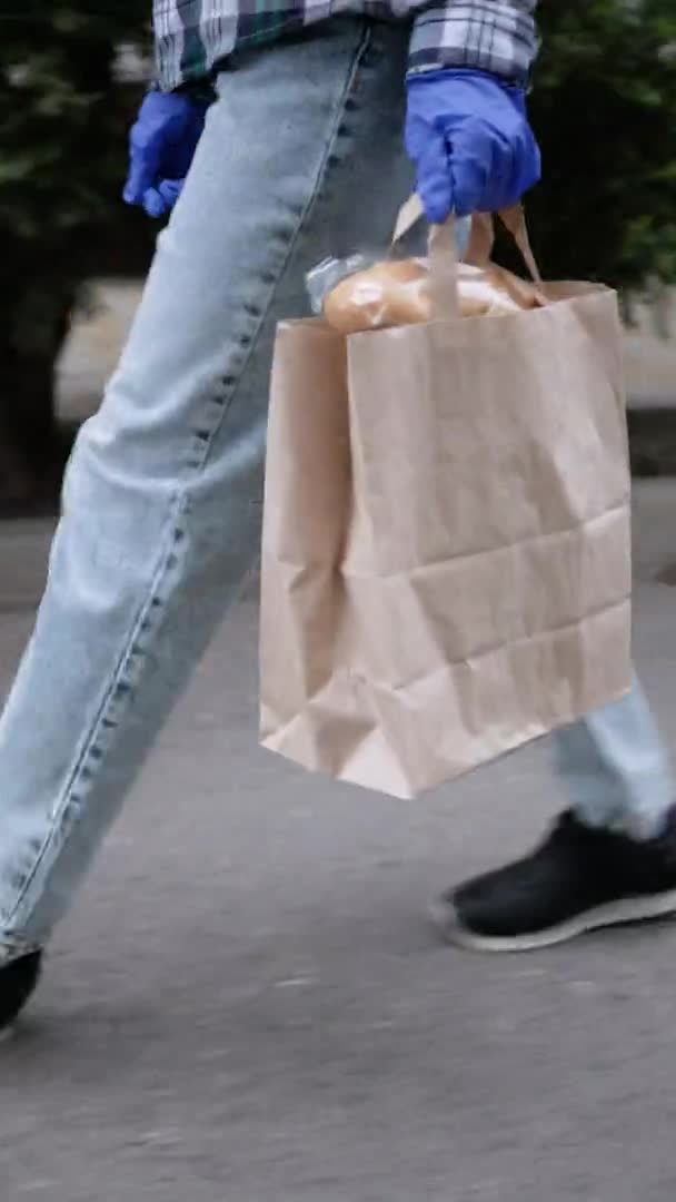 El mensajero entrega comida a casa. Entrega de alimentos en cuarentena. Quédate en casa. Vídeo vertical — Vídeos de Stock