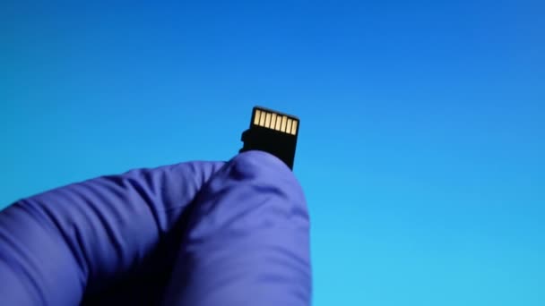 El trabajador técnico de mantenimiento en la reparación de tarjetas micro SD en el centro de servicio sobre fondo azul — Vídeos de Stock