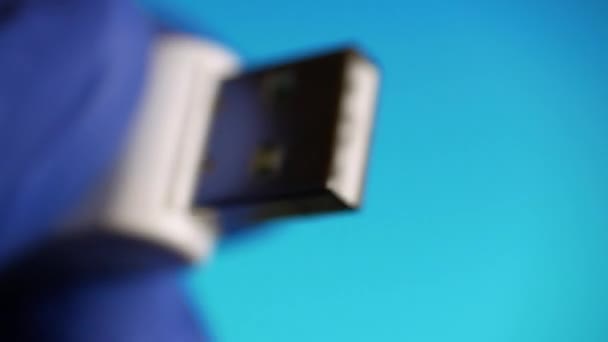 Gros plan de la carte mémoire du lecteur flash USB est dans les gants bleus sur fond bleu