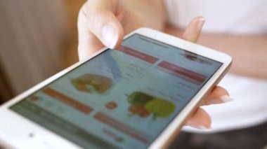 Kadın marketten sebze seçiyor. Kadın akıllı telefon kullanarak çevrimiçi bir mağazadan yemek sipariş ediyor. Evde akıllı telefon kullanan bir kadın internet dükkanından alışveriş yapıyor. 4K