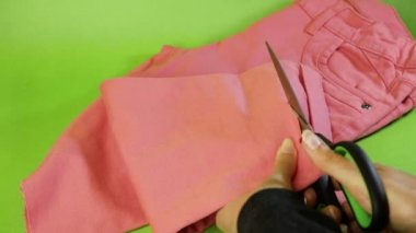 Kadın ucube, pembe kotu makasla kesti, kesti. Makasla kumaş kesen terziyi kapatın.