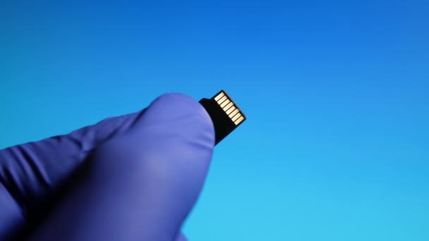 Micro-SD-Speicherkarte in der Hand Nahaufnahme auf blauem Hintergrund — Stockvideo