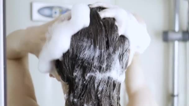 Mladá brunetka žena myje vlasy šamponem ve sprše s, péče o vlasy, opláchnout šampon, ceratin maska, a balzám, mytí vlasů — Stock video