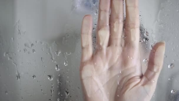 Onherkenbare vrouw raakt glas aan terwijl ze douchepalm neemt op bezweet glas in de douche. Handdia 's op glas — Stockvideo