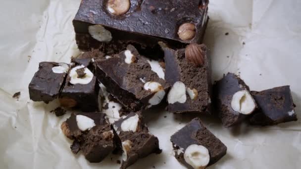 Chocolate bar cut into chunks with whole hazel nuts tasty dessert close up — Stock Video