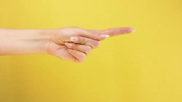 Female hand shows on someone and calls to his gestures closeup isolated on yellow background — Stock Video