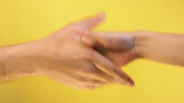 Sarı arka planda çıplak kadın ve erkeğin el sıkışması izole edildi. Kadın ve erkek elleri selamlıyor