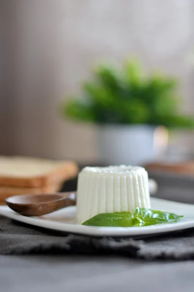 Čerstvý sýr s bazalkou listy na bílé plotně a tabulku s — Stock fotografie