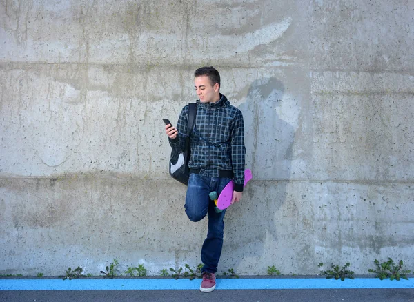 Tiener met schaatsen kijken uw smarphone — Stockfoto