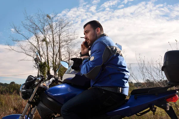 Motociclista hablando por teléfono con su teléfono inteligente —  Fotos de Stock