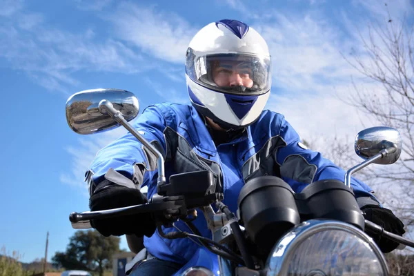 Motociclista com capacete azul passando por uma estrada — Fotografia de Stock