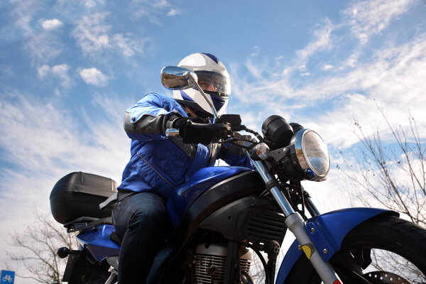 biker with helmet blue going by a road 