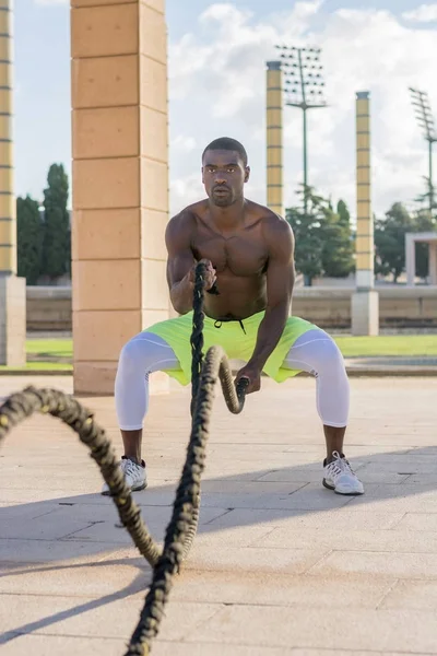 Treinamento muscular masculino com cordas de batalha e máscara de treinamento — Fotografia de Stock
