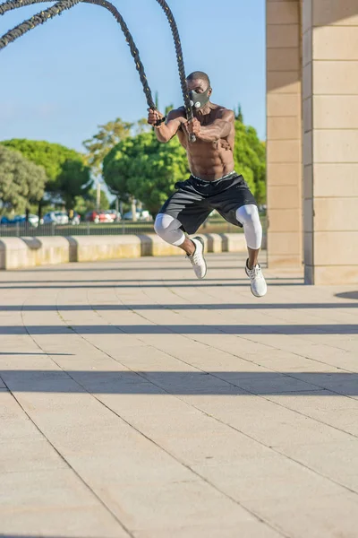 Treinamento muscular masculino com cordas de batalha e máscara de treinamento — Fotografia de Stock