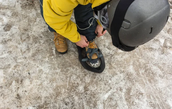 Um homem desportivo vestindo suas botas de neve para começar uma excursão de montanha nevada . — Fotografia de Stock