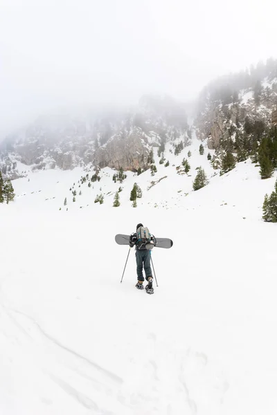 Cavaleiro livre com sapatos de neve e snowboard em suas costas . — Fotografia de Stock