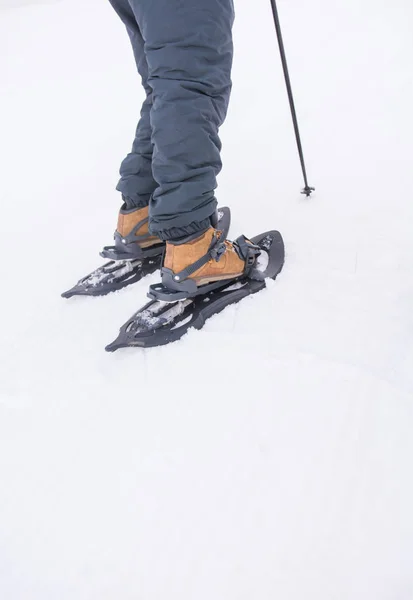 Ein sportlicher Mann zieht seine Schneeschuhe an, um eine verschneite Bergtour zu starten. — Stockfoto