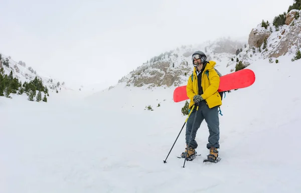 En sportig man sätter på sig snöskor för att starta en snöig fjällutflykt. — Stockfoto
