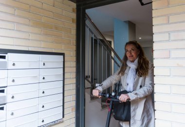 Kadın, çevreye yardım etmek için elektrikli scooterıyla işe gitmeye hazırlanıyor.