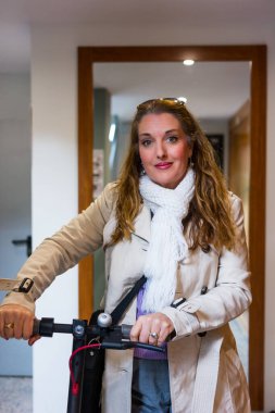 Kadın, çevreye yardım etmek için elektrikli scooterıyla işe gitmeye hazırlanıyor.