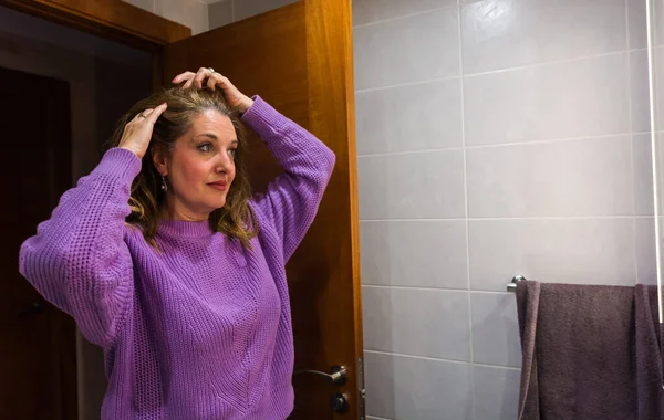 40歳の女性が化粧をし 仕事に行く前にバスルームで彼女の肌の世話をする ストックフォト