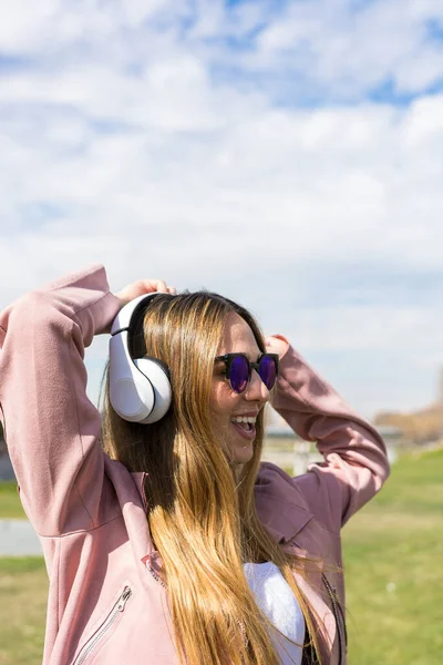 若い幸せな女の子は春の日に彼女のヘッドフォンで音楽を聴きながら踊っています — ストック写真