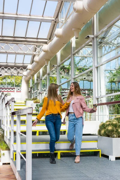 Two friends walk through a park and tell each other their secrets while laughing and taking pictures