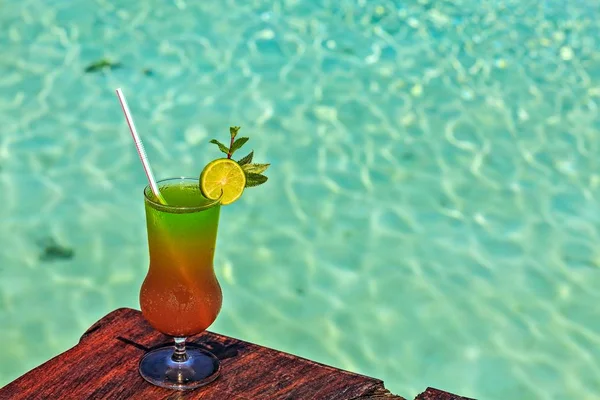 Il bicchiere di bevanda è su un tavolo da spiaggia Fotografia Stock