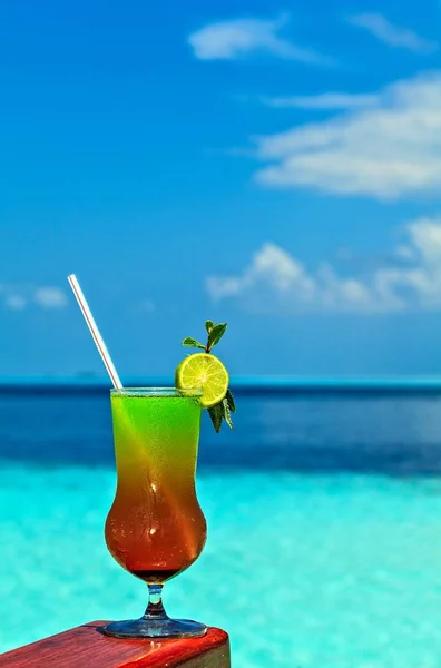 Un vaso de bebida está en una mesa de playa —  Fotos de Stock