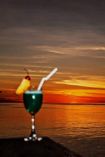 Copo de bebida está em uma mesa de praia Imagens Royalty-Free