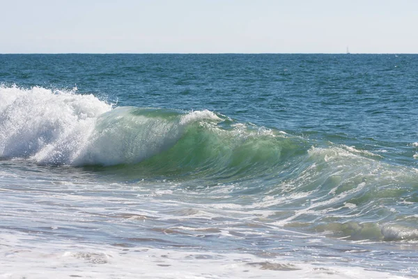Güzel bir deniz dalgası kırılıyor ve hoş renkler yaratıyor.