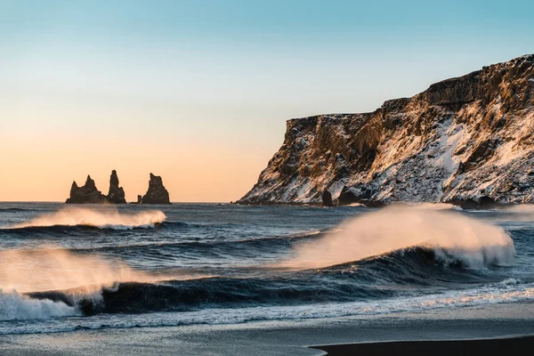 Playa de arena negra muy conocida en la ciudad de Vik en Islandia durante la puesta del sol de invierno. Paisaje islandés hermoso, turismo, paisaje dramático — Foto de Stock