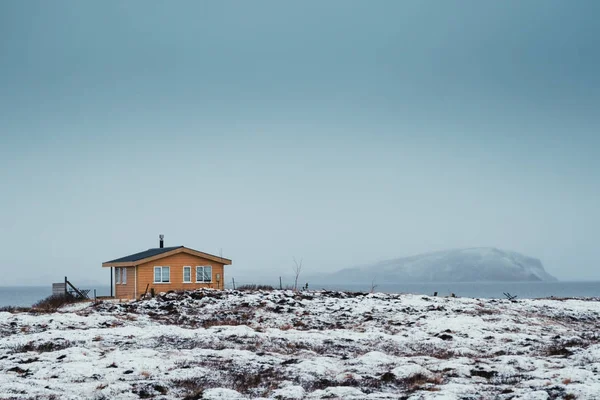 Isolierte kleine Holzhütte im Winter Island mit einem See und Berg im Hintergrund. Orangen- und Krickente-Foto — Stockfoto