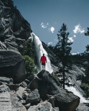 Yosemite Vadisi 'nde büyük bir şelalenin önünde duran maceraperest bir adam. Maceracı insanlar. Instagram biçimi fotoğrafı