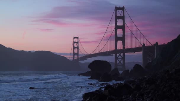 Un hermoso metraje cinematográfico del puente Golden Gate durante el atardecer. Hora dorada en San Francisco en California. Arquitectura histórica de los Estados Unidos de América — Vídeos de Stock