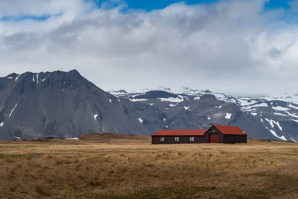 Enskilt hus i ett dramatiskt landskap av isländsk typisk natur med höga och skarpa berg och långa platta marker. Vacker natur på Island — Stockfoto