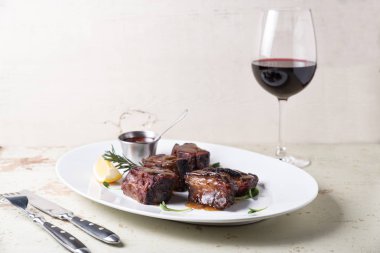 büyük beyaz plaka üzerinde bir kadeh kırmızı şarap ile hizmet ızgara kaburga