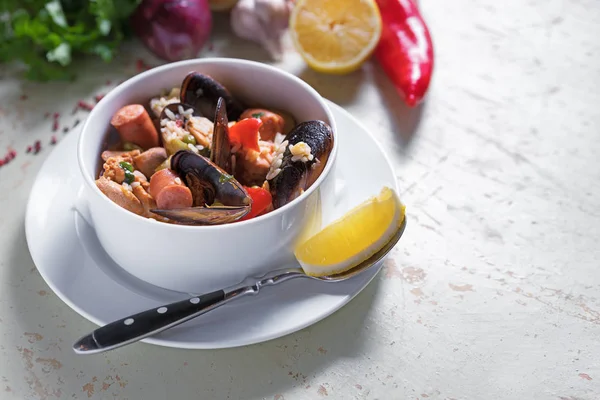 Paella safran pirinç, bezelye, karides, midye, mürekkep balığı, et ile beyaz tabak içinde. Deniz ürünleri paella, geleneksel İspanyol yemeği.