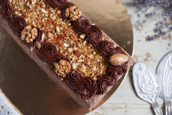 En bit av läcker chokladkaka med grädde och valnötter på en tallrik. Utrymme för text, trä bakgrund — Stockfoto