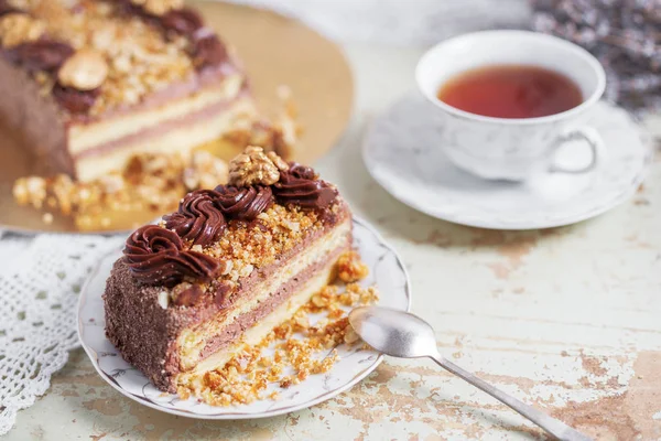 Uma fatia de delicioso bolo de chocolate com creme e nozes em um prato. Espaço para texto, fundo de madeira — Fotografia de Stock