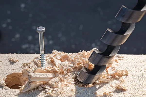 Boer de aço perfurar um buraco em uma placa de madeira. Variedade de ferramentas de carpintaria e instrumentos de serralheiro close-up . — Fotografia de Stock