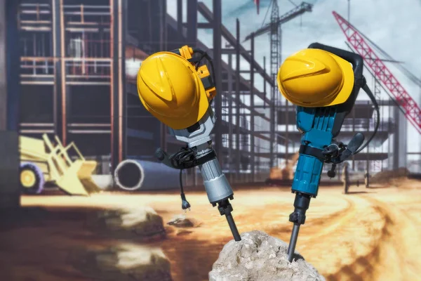İki elektrik matkaplı ve kask, sopa dışarı bir beton blok.