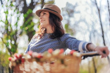 Şapkalı bir vintage Onun Bisiklet ile bir parkta genç bayan.